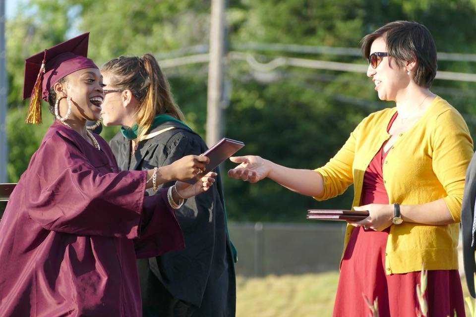 Paula Villescaz handing a diploma to a graduating student